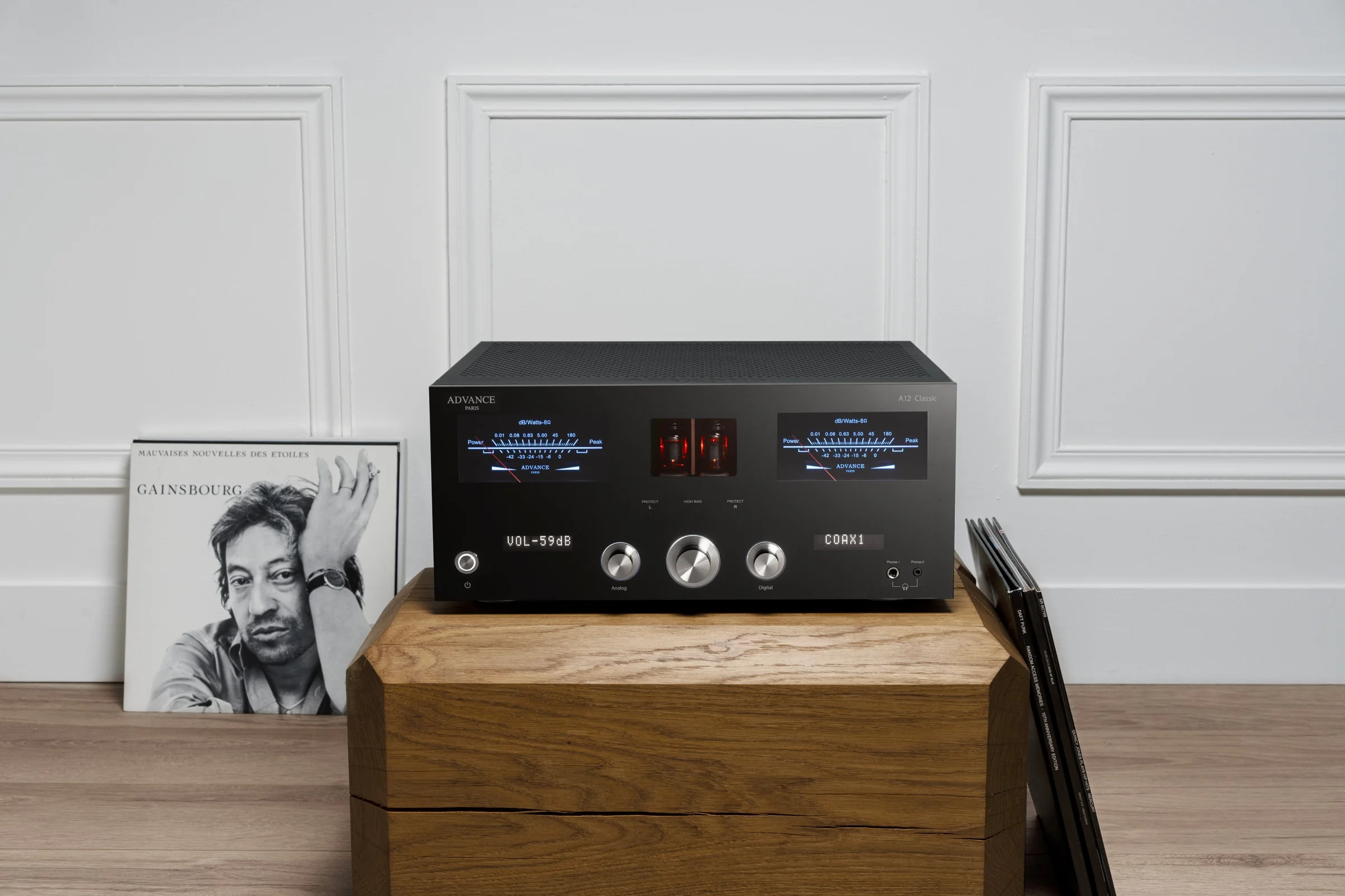 An Advance Paris integrated amplifier on a wooden sideboard beside a record sleeve, VU meters lit