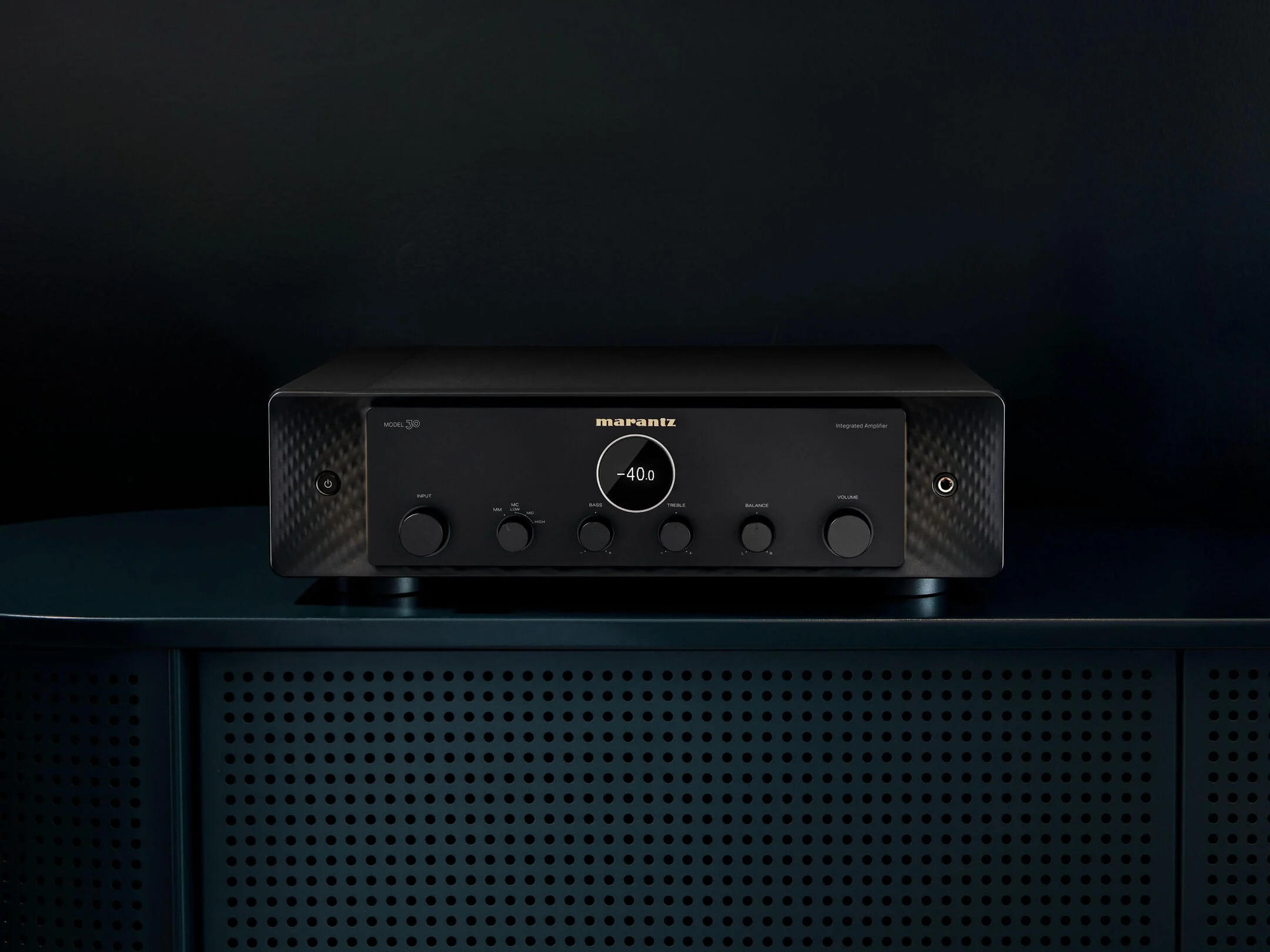 A Marantz amplifier in black on a dark cabinet, dial glowing