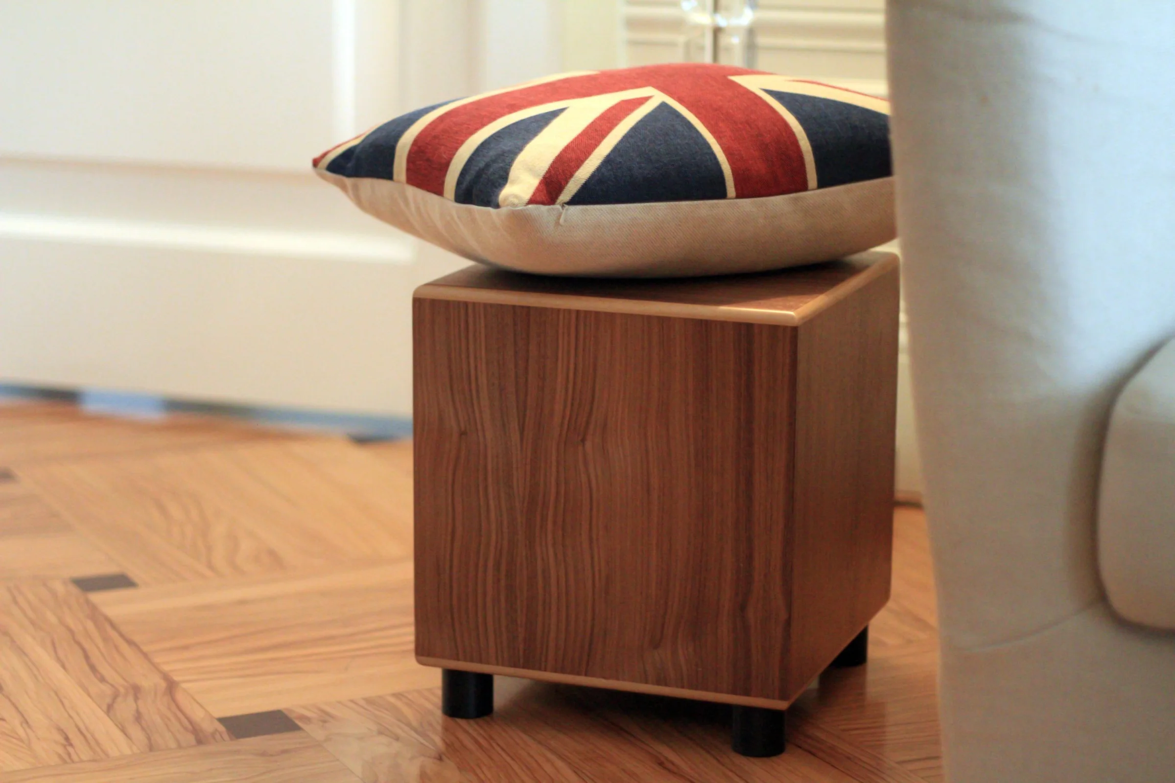 An MJ Acoustics subwoofer in walnut, a Union Jack cushion resting on top